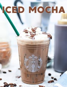 a starbucks drink with whipped cream and chocolate shavings on the table next to coffee beans