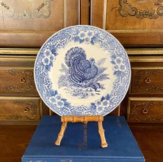 a blue and white plate sitting on top of a wooden stand in front of drawers