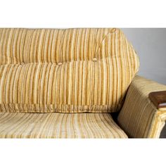 an upholstered chair with a wooden armrest and foot rest in yellow striped fabric