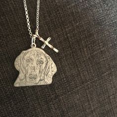 a silver necklace with a cross on it and a dog's head in the middle