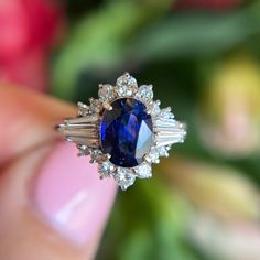 a close up of a person holding a ring with a blue and white stone in it