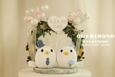 two white birds on top of a cake with balloons in the shape of hearts and flowers