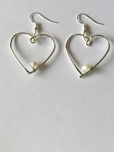 Open silver plated wire heart white fresh water Pearl minimalist dangle earrings. The silver plated wire is tarnish resistant and nickel and lead free. The earring hooks are silver plated and nickel and lead free. This is a perfect gift for a Valentine! Silver Heart-shaped Pearl Earrings For Valentine's Day, White Dangle Heart Earrings With Ear Wire, Nickel-free White Sterling Silver Heart Earrings, Dainty Silver Metal Heart Earrings, Dainty Silver Heart Metal Earrings, Minimalist Sterling Silver Heart Earrings With Ear Wire, Dainty Silver Heart Earrings, Minimalist Heart-shaped Metal Earrings, Silver Dangle Heart Earrings With Pearl Drop