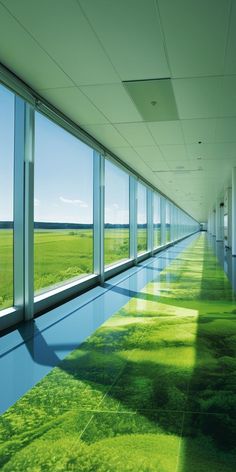 an empty hallway with large windows and green grass on the ground in front of it