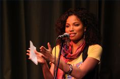 a woman standing in front of a microphone holding a piece of paper with her right hand