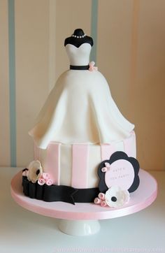 a white and pink wedding cake with a dress on top