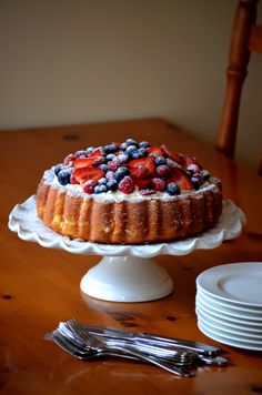 a cake sitting on top of a wooden table next to plates and utensils