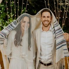 a man and woman dressed in wedding attire standing next to each other under a veil