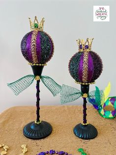 two purple and green ornaments are sitting on top of a table next to some beads