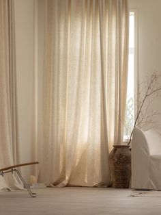 a living room with white furniture and curtains