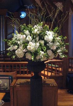 a vase with white flowers on top of a table in front of a pipe organ