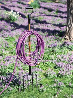 a purple garden hose is attached to a metal pole in the middle of a field