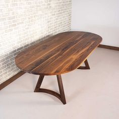 a wooden table sitting on top of a white floor next to a brick wall in a room