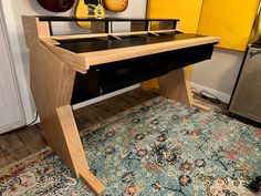 a wooden desk sitting on top of a rug next to a yellow guitar case and amp