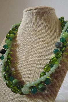 "Cracked green agate, jade, cats' eye, and faceted stones are gorgeous in this fresh design. This multi strand necklace is 19\" and is finished with a silver hook clasp. The design can also be worn untwisted.  All orders come in a beautiful gift box ready for giving along with a special \"thank you\" gift. Thank you for sharing my love of jewelry." Green Multi-strand Beaded Necklace With Natural Stones, Green Multi-strand Necklace With Natural Stones, Green Agate Jewelry With Faceted Beads, Green Crystal Necklaces With Faceted Beads, Adjustable Green Double Strand Necklace, Elegant Green Crystal Necklaces With Faceted Beads, Green Jade Necklaces With Faceted Beads, Green Jade Necklace With Faceted Beads, Adjustable Green Double Strand Beaded Necklace