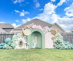 a house decorated with balloons and decorations in front of a fenced in lawn area