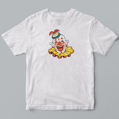 Back in the day, people thought clowns were funny - professionals who entertained audiences with humor and pantomime. Boy do we think differently today! Whether clowns amuse or terrify you, you'll love this t-shirt featuring a delightfully creepy old-school circus clown. Adult unisex regular fit 100% combed pre-shrunk cotton t-shirt available in sizes s-xxl and printed in Nashua, NH.* Pre-Shrunk 100% Combed Ringspun Cotton* Anvil by Gildan Adult Unisex Regular Fit T-Shirt.* Available In Sizes S, Novelty White T-shirt For Streetwear, White Novelty T-shirt For Streetwear, Funny White Graphic T-shirt, Funny White T-shirt With Graphic Design, Funny White Graphic Design T-shirt, Circus Clown, Pantomime, Feather Hat, Back In The Day