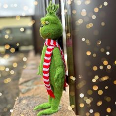 a green stuffed animal with a red and white striped scarf