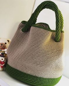 a crocheted purse sitting on top of a white shelf next to a teddy bear