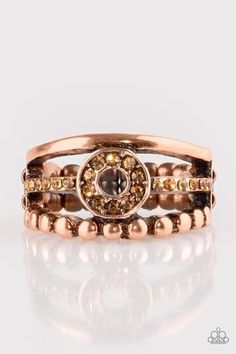 A smooth and dotted copper band flank a topaz rhinestone encrusted band, creating glittery layers across the finger. Encrusted in golden topaz rhinestones, a circular frame is pressed into the center of the bands for a refined finish. Features a dainty stretchy band for a flexible fit. Sold as one individual ring. Adjustable Gold Crystal Ring, Gold Crystal Ring With Bling, Elegant Rose Gold Copper Rings, Adjustable Crystal Ring With Rhinestones, Adjustable Crystal Rhinestone Ring, Gold Crystal Ring With Rhinestones For Party, Gold Rings With Rhinestones, Gold Rings With Bling, Gold Topaz Crystal Ring