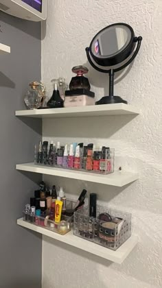 three white shelving shelves with cosmetics and makeup products on them in front of a mirror