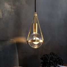 a modern light fixture hanging from the ceiling in a room with dark walls and furniture