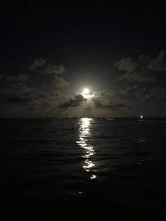 the full moon shines brightly in the night sky over the ocean with dark clouds