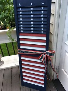 an american flag made out of shutters on a porch with red, white and blue ribbons