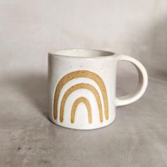 a white coffee cup with a rainbow painted on it