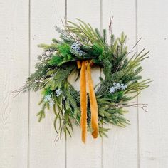 a wreath hanging on the side of a white wooden wall covered in snowflakes