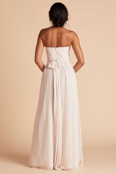 the back of a woman wearing a white strapless dress with a bow at the waist