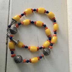 "Yellow glass bead necklace 3 large silver beads with raised design Small red and blue beads 20\" long Yellow beads .5\" long , .26\" wide Condition - very good vintage" Adjustable Amber Beaded Necklace With Large Beads, Festival Large Bead Czech Glass Necklaces, Festival Czech Glass Beaded Necklaces With Large Beads, Traditional Czech Glass Necklace With Polished Beads, Traditional Necklace With Polished Czech Glass Beads, Spiritual Yellow Jewelry With Large Beads, Yellow Jewelry With Large Oval Beads, Yellow Polished Beads For Festivals, Polished Oval Beads Necklaces For Festival