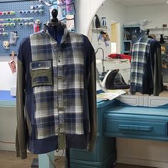 a blue and white checkered shirt hanging on a clothes rack in front of a mirror