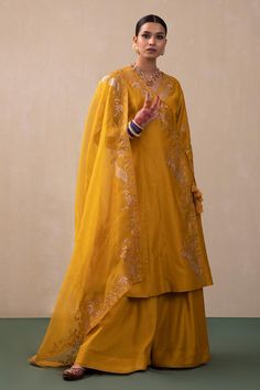 Mustard angrakha featuring embroidered zari mor motifs highlighted with sequin work. Comes with plain sharara and dupatta.
Components: 3
Pattern: Hand Embroidery
Type Of Work: Zari, Mor
Neckline: V Neck
Sleeve Type: Three Quarter Sleeves
Fabric: Silk Chanderi, Dupatta: Organza
Color: Yellow
Other Details: 
Overlap kurta panels with drawcord closure
Occasion: Sangeet - Aza Fashions Traditional Chanderi Palazzo Set With Gota Work, Traditional Drape Chanderi Palazzo Set With Gota Work, Chanderi Palazzo Set With Gota Work, Designer Raw Silk Palazzo Set For Transitional Season, Traditional Slub Silk Palazzo Set With Dupatta, Traditional Drape Cotton Silk Palazzo Set With Zari Work, Slub Silk Palazzo Set With Traditional Drape, Traditional Chanderi Palazzo Set For Designer Wear, Traditional Chanderi Palazzo Set For Transitional Season