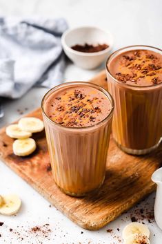 two glasses of chocolate banana smoothie on a cutting board