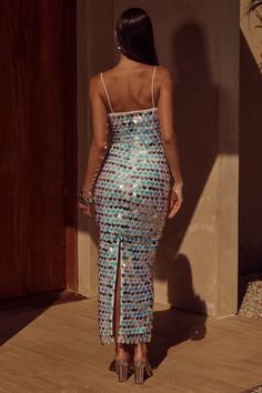 a woman in a blue and silver sequin dress standing on a wooden floor with her back to the camera