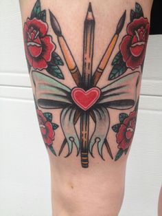 an artistic tattoo design on the leg of a woman with scissors and roses around her ankles