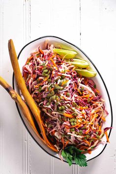 a bowl filled with coleslaw and carrots on top of a white table