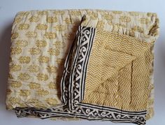 two yellow and black bedspreads on a white surface with an intricate design