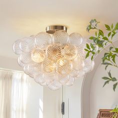 a light fixture hanging from the ceiling in a room with white walls and plants on it