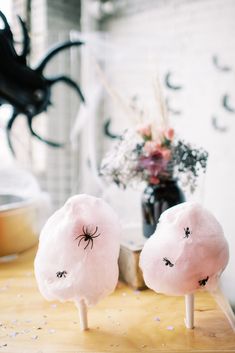 two cotton candy lollipops with eyes drawn on them sitting on a table