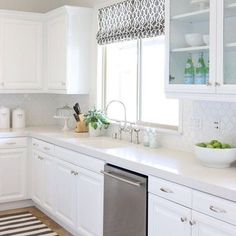 a kitchen with white cabinets and counter tops