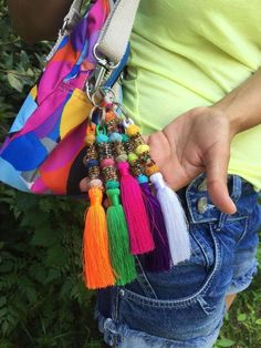 a person holding a multicolored purse with tassels and beads on it