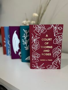 three books sitting on top of a table next to a vase with flowers in it