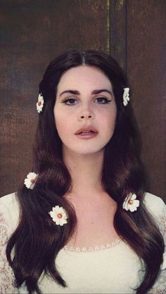 a woman with long brown hair and flowers in her hair, wearing a white dress