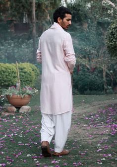 The jalalgarh kurta in powder pink is a charming and sophisticated choice for Indian grooms, ideal for haldi, mehndi, or sangeet ceremonies. Crafted from a luxurious blend of viscose cotton silk and georgette, this kurta offers a smooth and breathable feel, perfect for long celebrations. The kurta comes with an ivory salwar, creating a balanced and harmonious ensemble. The jalalgarh kurta is perfect for grooms who want a contemporary yet traditional outfit. Pair it with traditional juttis or modern footwear for a polished and sophisticated appearance. Pink Kurta, Traditional Outfit, Indian Groom, Bespoke Tailoring, Kurta Set, Powder Pink, Photographic Lighting, Cotton Silk, Traditional Outfits