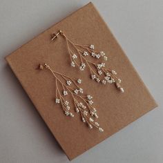 two pairs of earrings with pearls hanging from them on top of a piece of brown paper