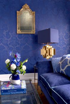 a living room with blue walls and floral arrangement on the coffee table in front of it