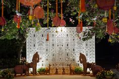 an elaborately decorated stage with elephants and flowers in the foreground, surrounded by hanging decorations