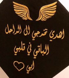 a black graduation cap with gold lettering and wings on the front, in arabic writing